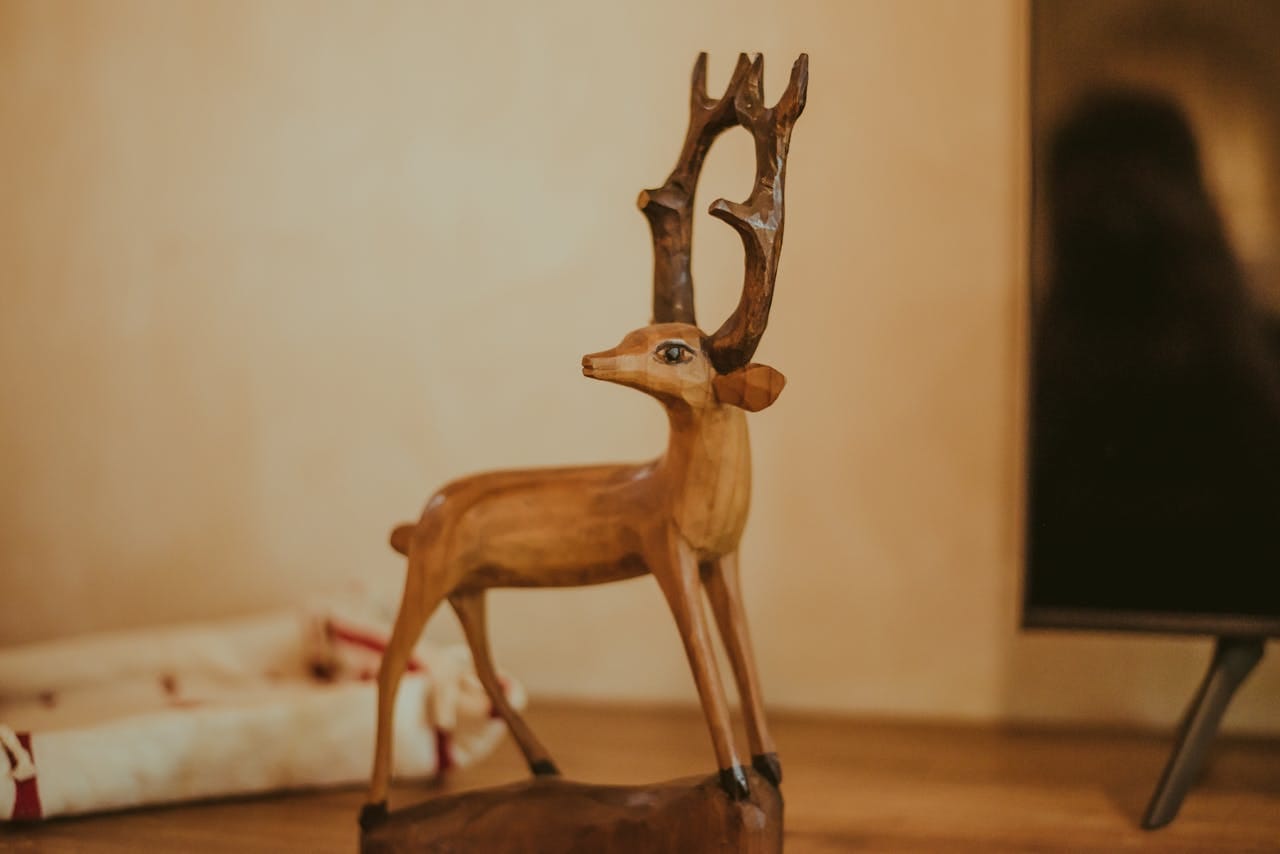 A detailed wooden deer sculpture on a table, showcasing fine craftsmanship in a cozy indoor setting.