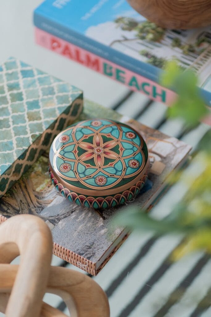 Stylish arrangement of decor with books, patterned boxes, and ornaments on a glass table.